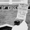 Protester holds sign reading 'When the books go out, the kids come back.' In the background, on a building, a sign reads 'Board of Education'