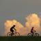 People ride bikes with cumulus clouds in the background, on the Mississippi River levee in Jefferson Parish, a suburb of New Orleans, Tuesday, July 14, 2020.