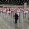 Voting stations with U.S. flags on them are set up in a large hall. A few people stand at different stations.