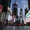This March 20, 2020 file photo, shows a screen displaying messages concerning COVID-19, right, in a sparsely populated Times Square in New York.
