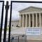 A black fence is in the foreground, the Supreme Court in the background. On the fence a sign reads 'area closed'