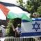 Counter protester Caren Ayden, of Pikesville, Md., carries an Israeli flag as students wave Palestinian flags during a demonstration against the Israel-Hamas war at George Washington University in Was