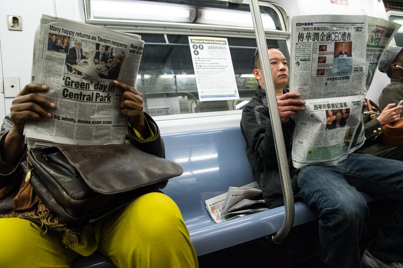 Passengers read newspapers in English and Chinese on the subway in Manhattan.