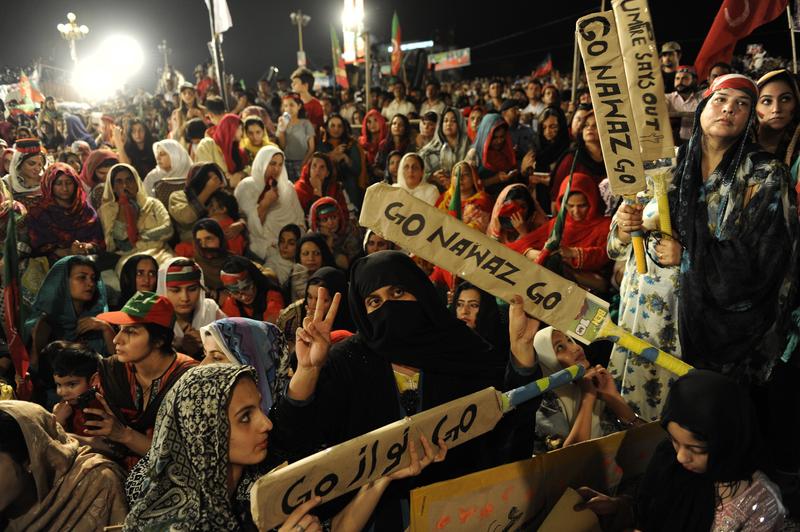 Pakistan Tehreek-i-Insaaf (PTI) supporters hold banners during ongoing anti-government protests in Islamabad's Red Zone, Pakistan on August 23, 2014.