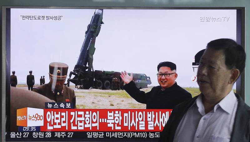 A man passes a TV showing an image of North Korean leader Kim Jong Un as he boasts of the success of a powerful new midrange ballistic missile test. June 23, 2016