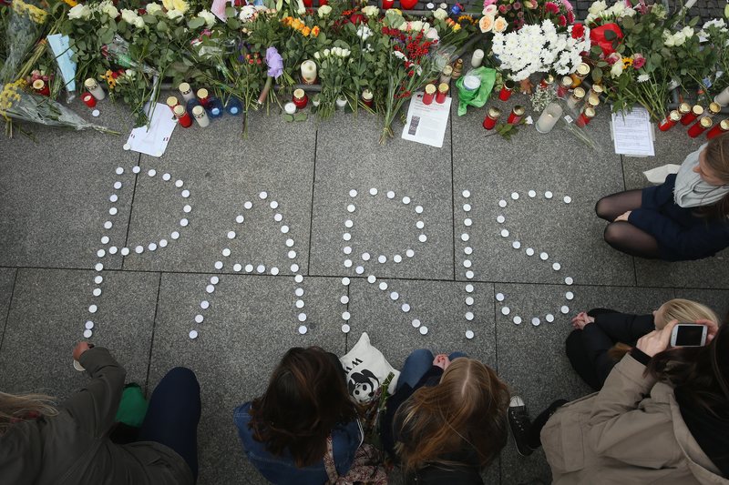 People finish arranging candles into the word 'Paris' next to flowers and messages left at the gate of the French Embassy following the recent terror attacks in Paris on November 14, 2015 in Berlin.