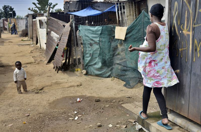 A woman walk in a dusty alley in the impoverished Diepsloot township outside Johannesburg on April 16, 2014.