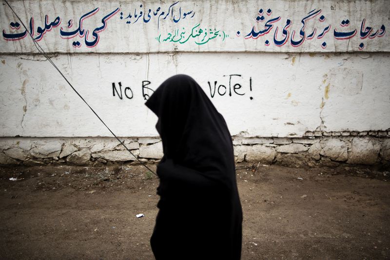 An Afghan resident walks past a graffiti slogan against the presidential election in the city of Herat on April 3, 2014. Afghans vote on April 5 for a successor to Hamid Karzai.