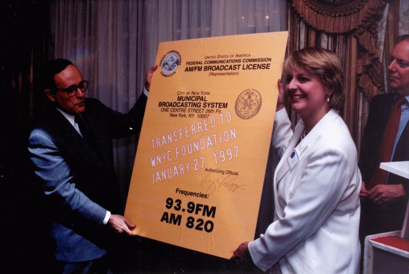 January 27, 1997, Mayor Giuliani hands WNYC CEO Laura Walker a copy of the official FCC Broadcast License, signifying the station's transfer to the WNYC Foundation.
