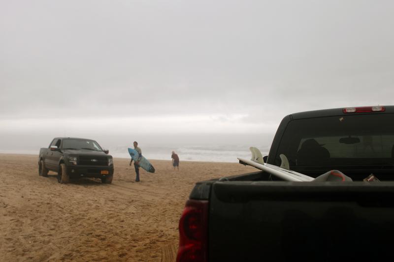 Trucks full of surfers and surfboards pull up on the town beach at Montauk on the Friday before Memorial Day. The surf was pounding and despite the fog and light drizzle, the beach was crowded.