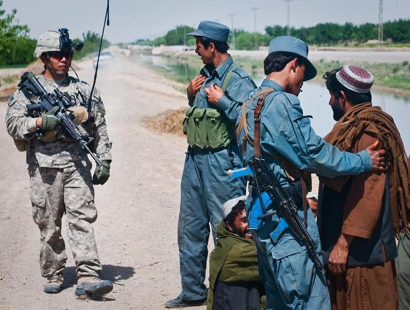 Afghan National Policemen and a U.S. Army Soldier from 3rd Platoon, Mad Dog Troop, 4th Squadron, 2nd Stryker Cavalry Regiment, interact with villagers while on patrol near Kandahar Airfield.