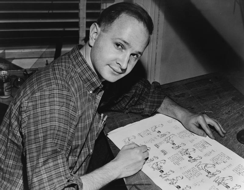 Jules Feiffer, American cartoonist, seated at work on cartoon.