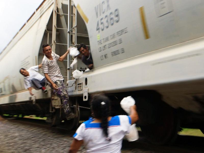 Volunteers such as this woman — who's with a group that calls itself "Las Patronas" — throw bags of food and water to migrants in Veracruz, Mexico, who are headed toward the U.S.-Mexico border.