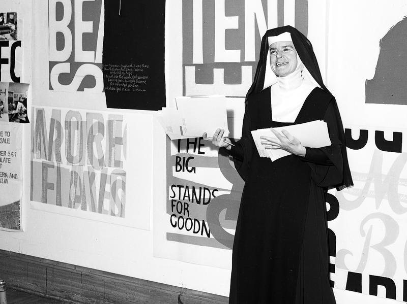 Sister Corita Kent stands in front of her work, including <em>for eleanor</em>, at Immaculate Heart College in 1964.