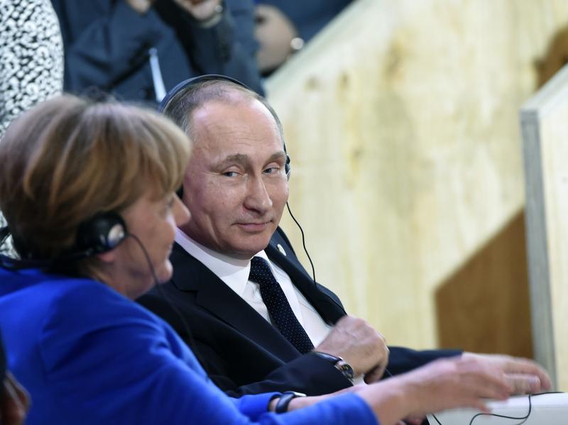 "I trust her, she is a very open person," Vladimir Putin said of German Chancellor Angela Merkel, seen here at last month's climate talks in Paris. But, he told the German daily <em>Bild</em>, "she is also subject to certain constraints and limitations."