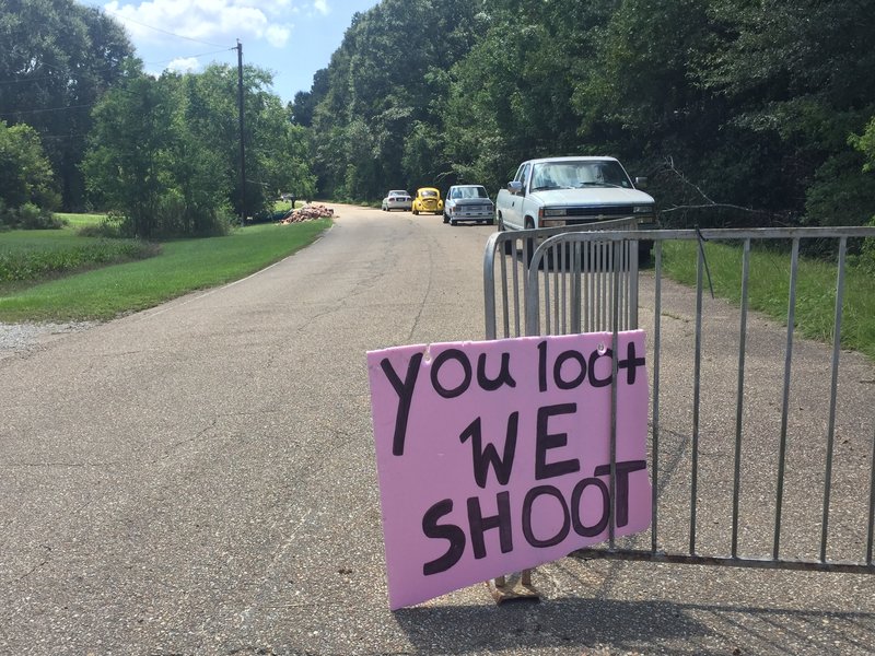 A handmade sign offers a stern warning at the entrance to an abandoned neighborhood where people have lost so much.
