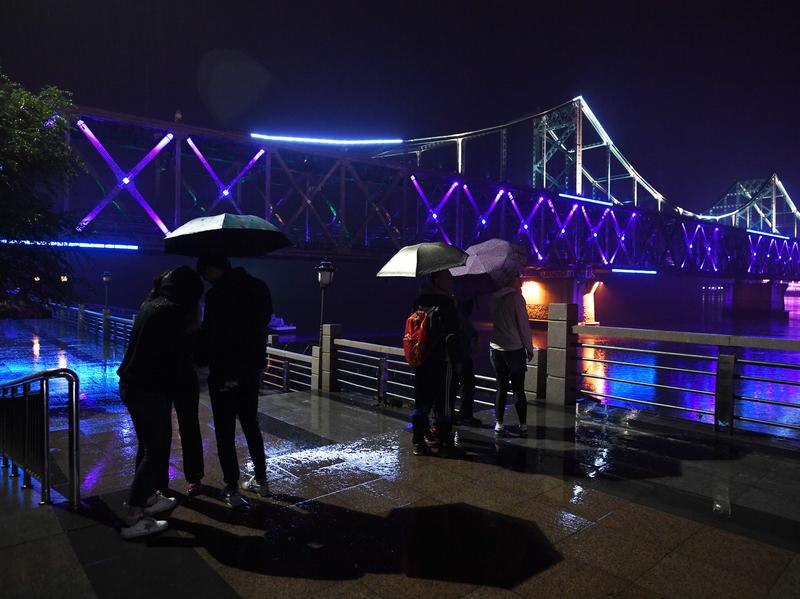 Visitors look at the China-North Korea Friendship Bridge across the Yalu River from Dandong, in northeast China. A company operating from Dandong is under fresh sanctions by the U.S.