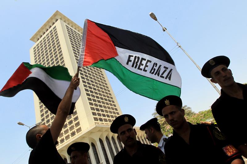 Egyptian protesters wave Palestinian flags with a Free Gaza slogan as they face riot police during a demonstration in front of Foreign Ministry headquarters in Cairo on May 31, 2010.