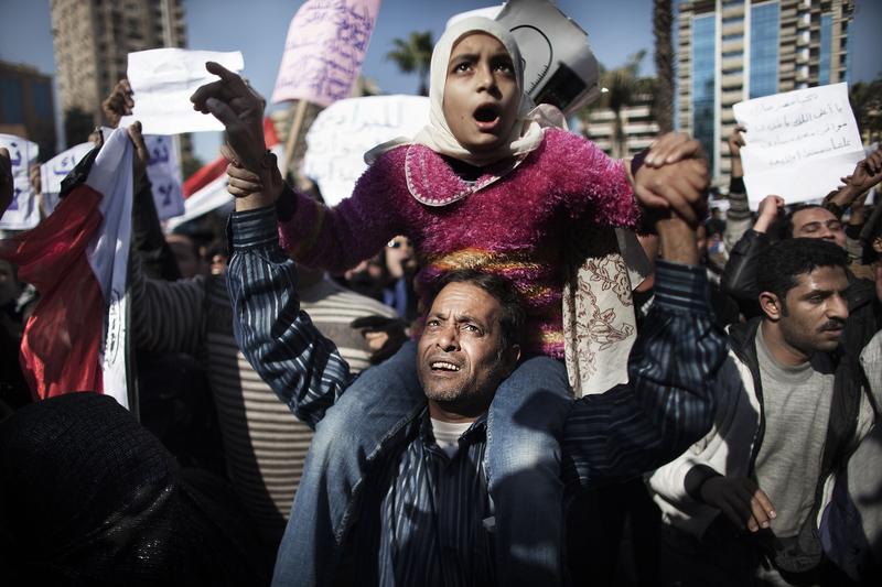 A supporter of Egyptian President Hosni Mubarak carries his daughter on his shoulder during a pro-regime demonstration in Cairo on February 2, 2011.