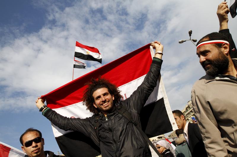 Egyptian anti-government demonstrators hold their national flag as they gather at Cairo's Tahrir Square on February 10, 2011.