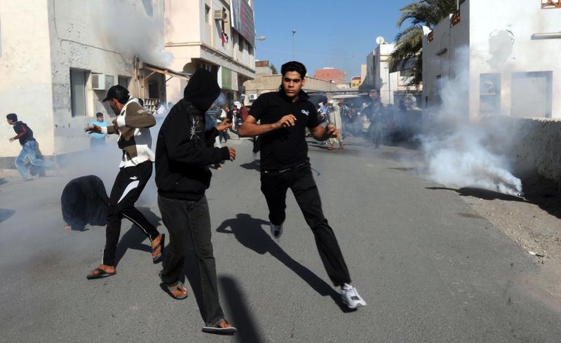 Bahraini protestors run for cover after police fired tear gas canisters to disperse them in the village of Diraz, northwest of Bahrain, on February 14, 2011