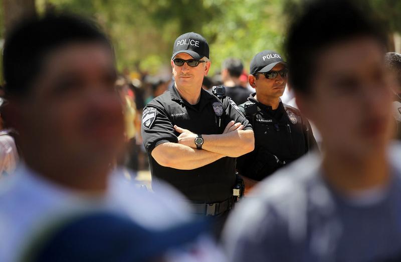 Police watch as opponents of Arizona's new immigration enforcement law gather outside the state capitol building.