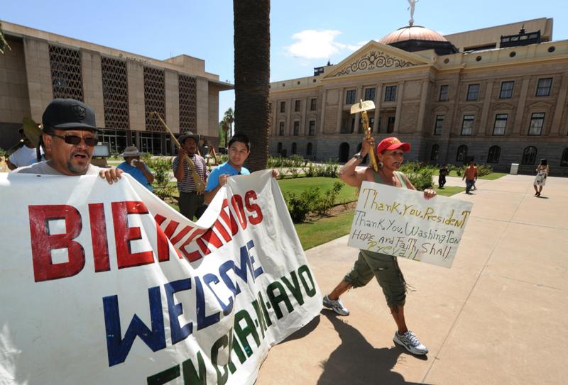 Protesters march past the Arizona State Capital Building as they campaign against the controversial state law SB1070