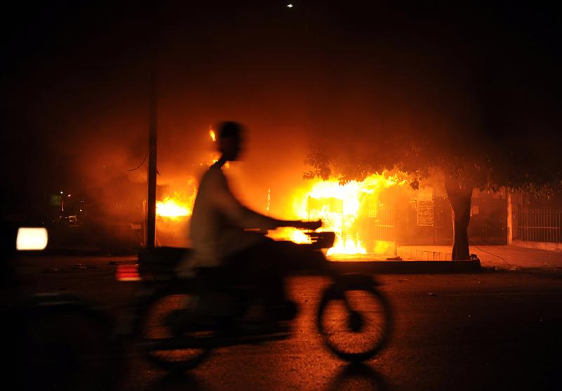 A Pakistani man rides past a burning shop in Karachi, Pakistan.
