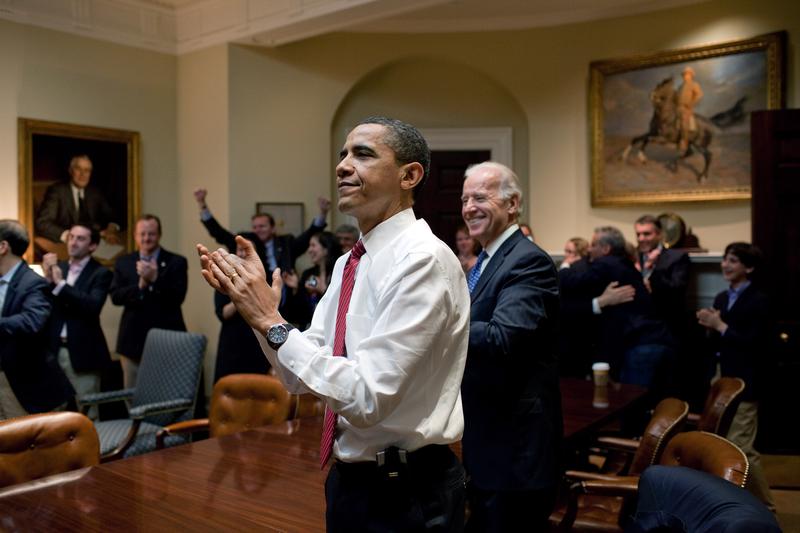 U.S. President Barack Obama, Vice President Joe Biden, and senior staff applaud in the Roosevelt Room of the White House, as the House of Representatives passes the health care reform bill.