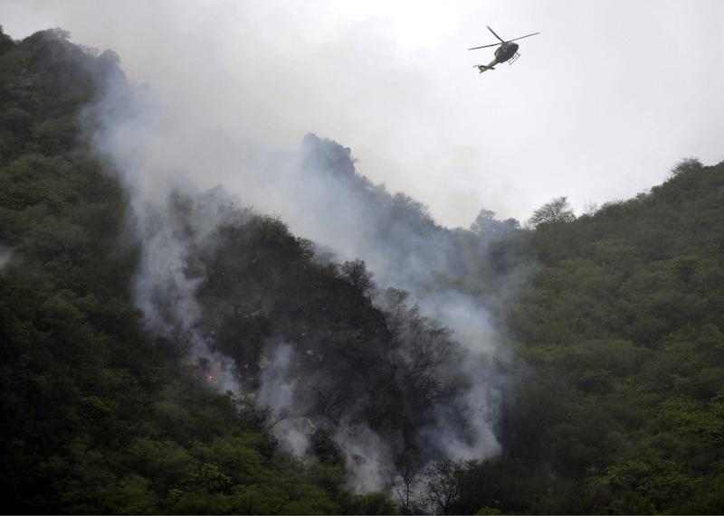 A Pakistani rescue helicopter flies over smoke and wreckage of a crashed passenger plane in The Margalla Hills on the outskirts of Islamabad on July 28, 2010.