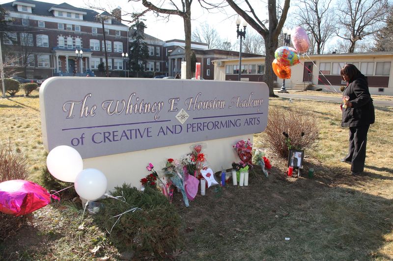 A woman leaves balloons at a memorial for Whitney Houston, outside of the school that bear's her name.