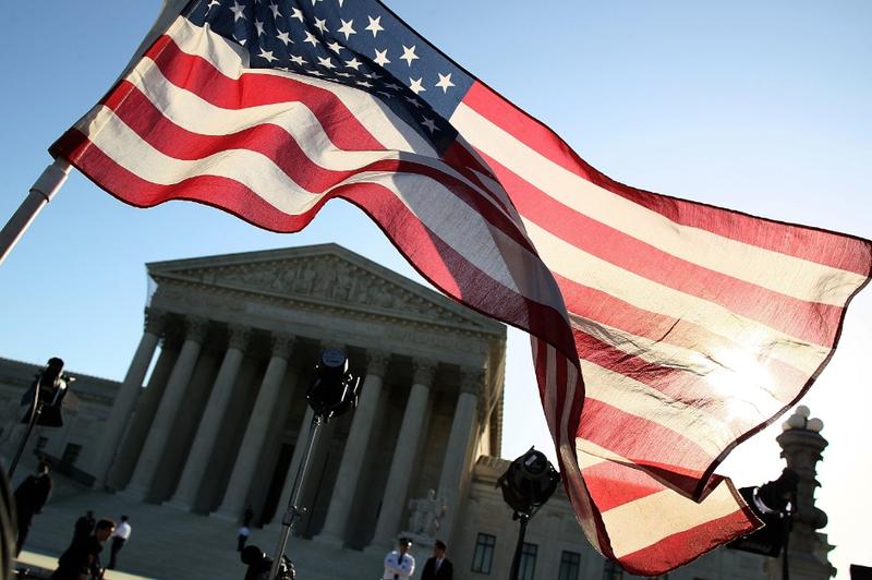 A person carries an American flag while marching in favor of the Patient Protection and Affordable Care Act in front of the U.S. Supreme Court.