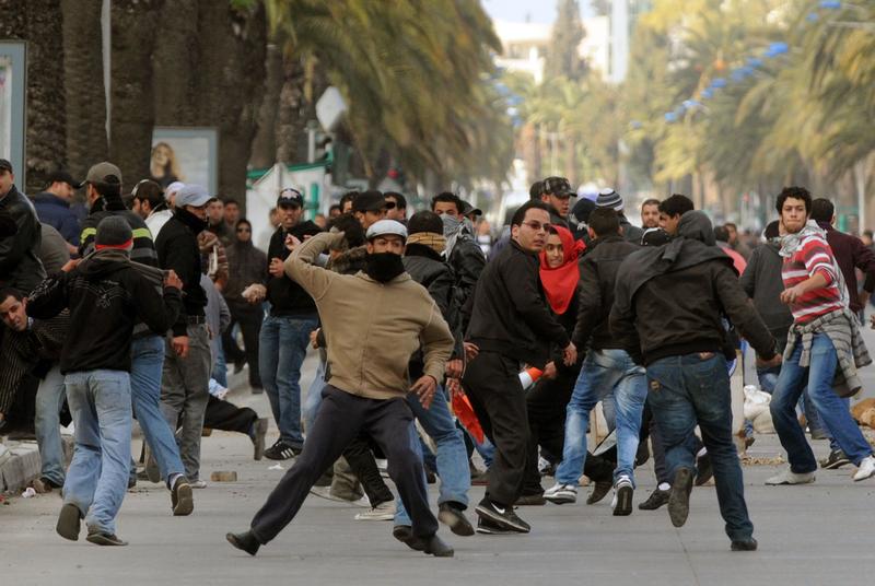 A Tunisian demonstrator throws a rock during clashes with security forces on Mohamed V avenue in Tunis on January 14, 2011. 