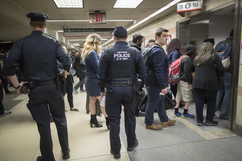 Amtrak police watch as passengers make their way to the track to board the first train to leave Penn Station after delays caused by a stuck train, Friday, April 14, 2017.