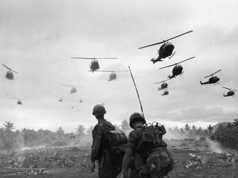 The second wave of combat helicopters of the 1st Air Cavalry Division fly over an RTO and his commander on an isolated landing zone during Operation Pershing.
