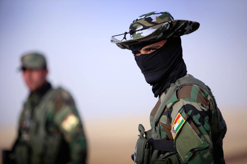 An Iraqi Kurdish security guard (Peshmerger) stands guard as Iraqi families fleeing violence in the northern Nineveh province gather at a Kurdish checkpoint in Aski kalak, 40 kms West of Arbil.
