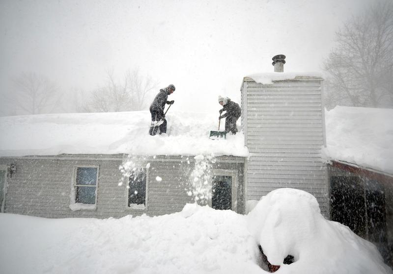 Tami Normile and Richard Brooks attempt to remove some of the five feet of snow from a roof top on November 20, 2014 in the Lakeview neighborhood of Buffalo, New York.