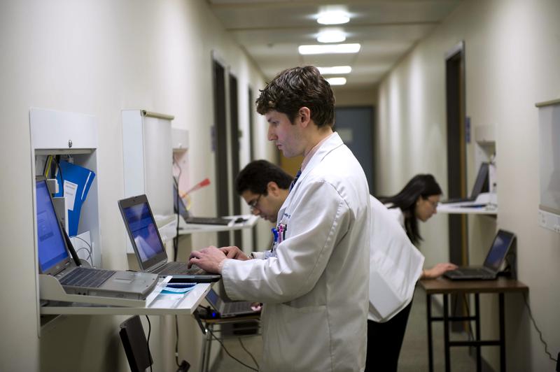 Gregory Shumer, center, Omer Shah, left, and Jasmine Zheng, all third-year Georgetown medical students, prepare to meet with a patient/actor in an exam room on the Georgetown Medical School.