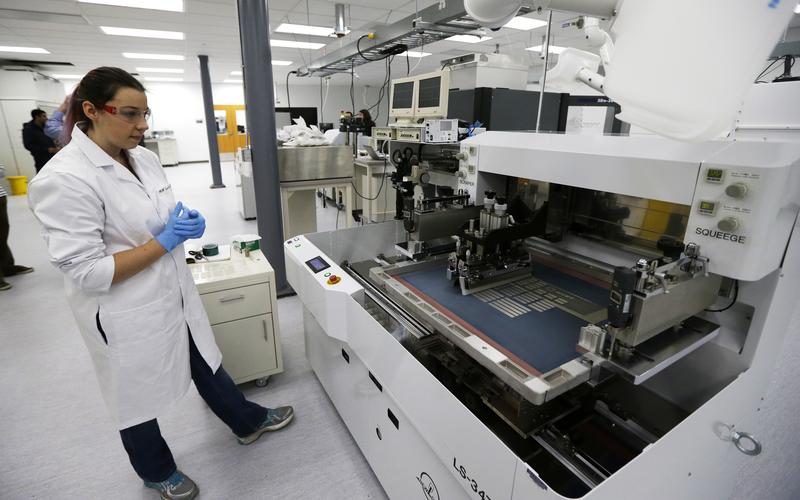 Caitlin Cramer, a PhD student in materials science engineering, demonstrates a machine that can print electrical circuits and solar cells at the newly opened Washington Clean Energy Testbeds lab.