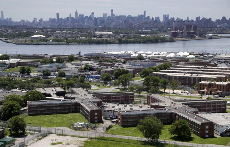 In this this June 20, 2014, file photo, the Rikers Island jail complex stands in the foreground with the New York skyline in the background.