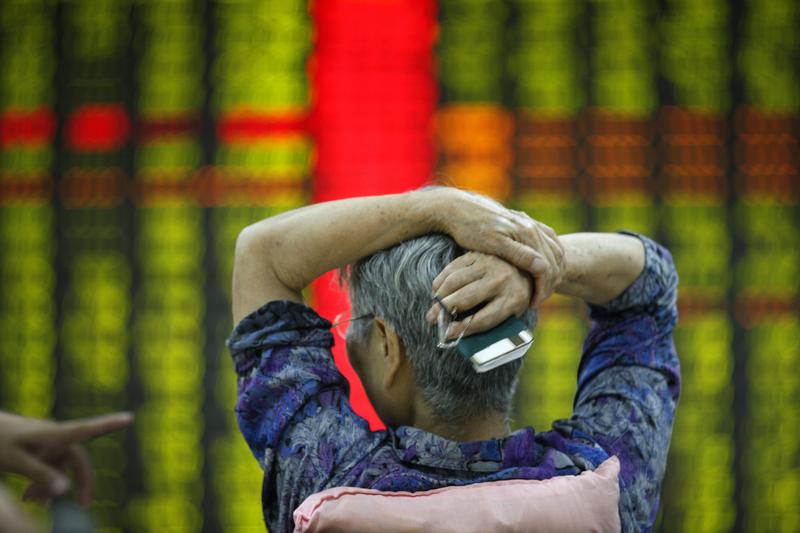 An investor watches market returns at a stock exchange hall in Tai an, China. Chinese shares dropped sharply on Monday.