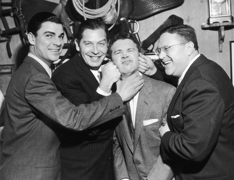 American television hosts Bert Parks (L) and Sam Levinson (R) along with American comic actor Milton Berle (1908 - 2002) pretend to beat up American comic actor Red Buttons (2nd from R).