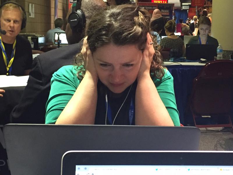 WNYC's Brigid Bergin holds her headphones close to her ears while sitting at Media Row on Wednesday at the DNC in Philadelphia.