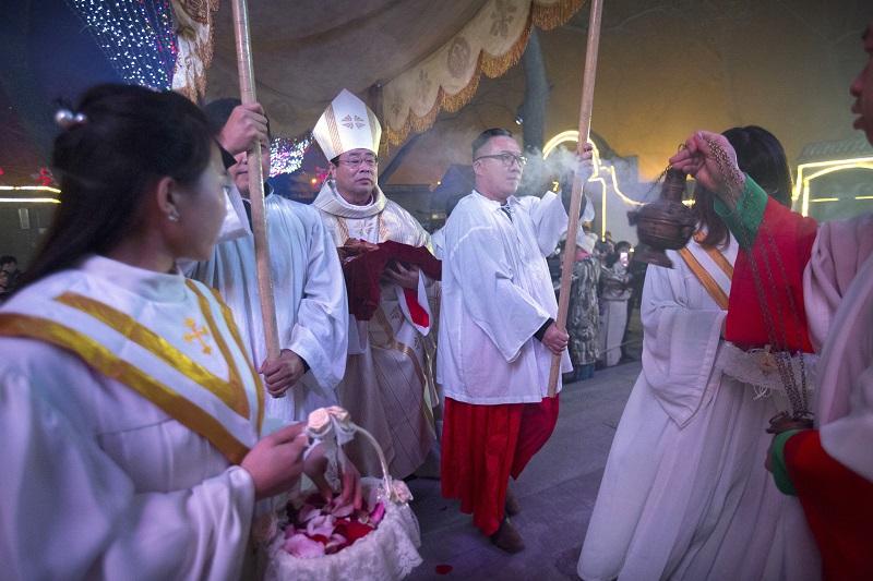 Chinese bishop Joseph Li Shan, center, holds a statue of the baby Jesus as he arrives for a Christmas Eve mass at the Southern Cathedral, Beijing, China, Thursday, Dec. 24, 2015.