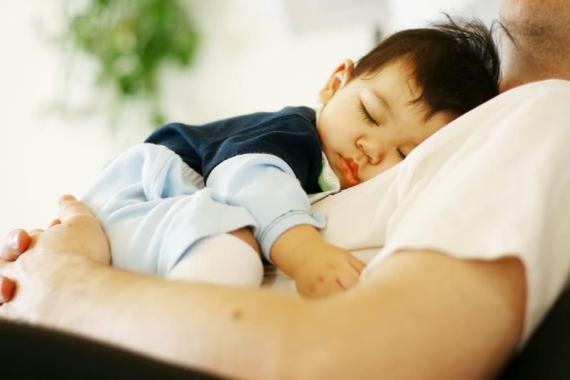 A baby snoozes on dad's chest.