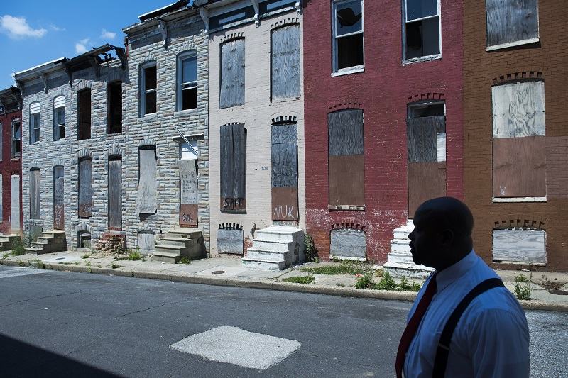 Dante Washington shown in shadow of his old, semi-blighted neighborhood in east Baltimore, MD on July 17, 2014.