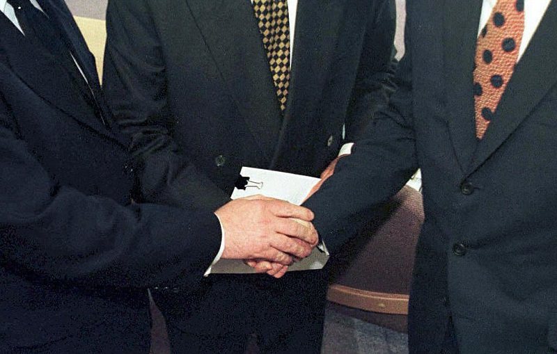 British Prime Minister Tony Blair (R) US Senator George Mitchell (C) and Irish Prime Minister Bertie Ahern shaking hands after they signed the historic agreement for peace in Northern Ireland, 4/1998.