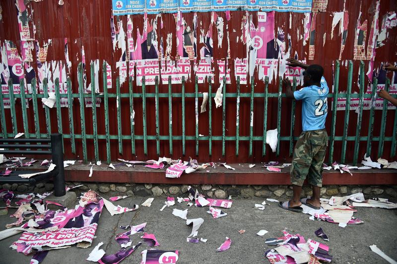 Demonstrators rip election posters of presidential candidate Jovenel Moise in Port-au-Prince on December 3, 2015, to protest against the election results.