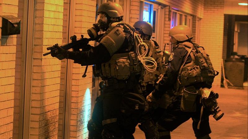 A swat team at a home in a scene from Craig Atkinson's "Do Not Resist."