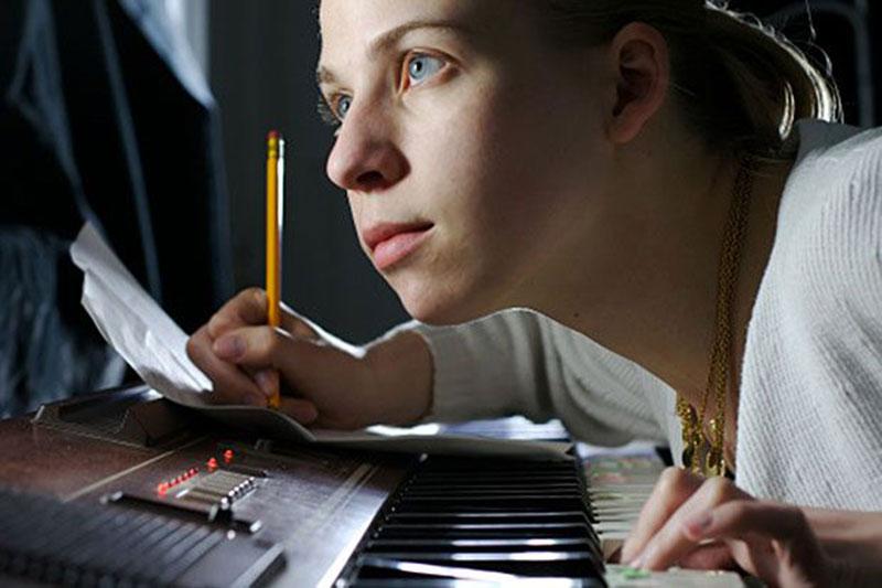 Young Woman Writing Music and Playing Piano